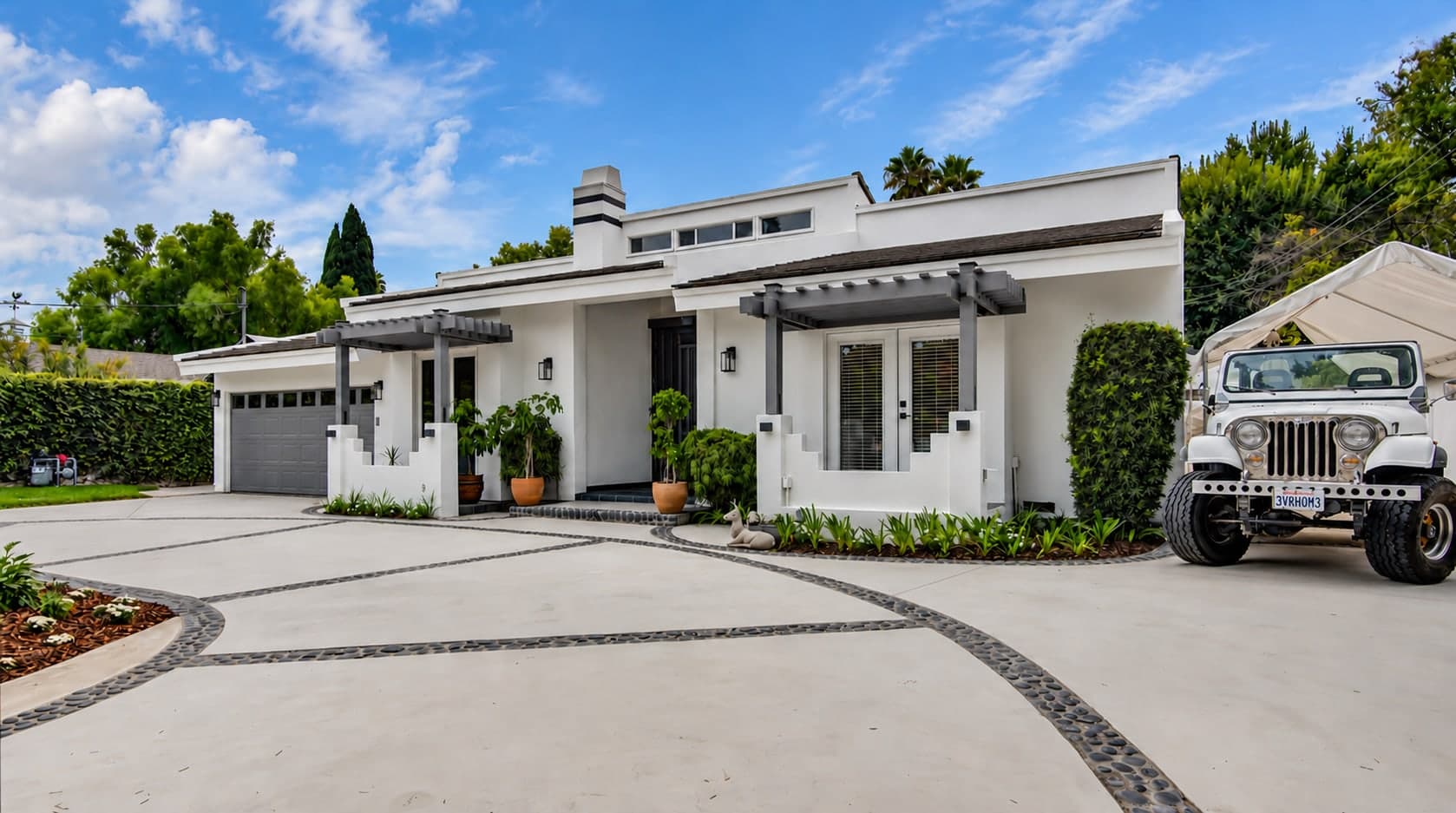Modern white home with a curved stone-inlay driveway at midday